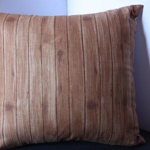 K&ouml;nnte beinhalten: Ein braunes Kissen mit Holzmaserung.