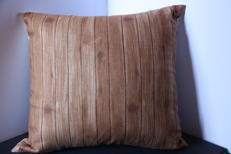 K&ouml;nnte beinhalten: Ein braunes Kissen mit Holzmaserung.