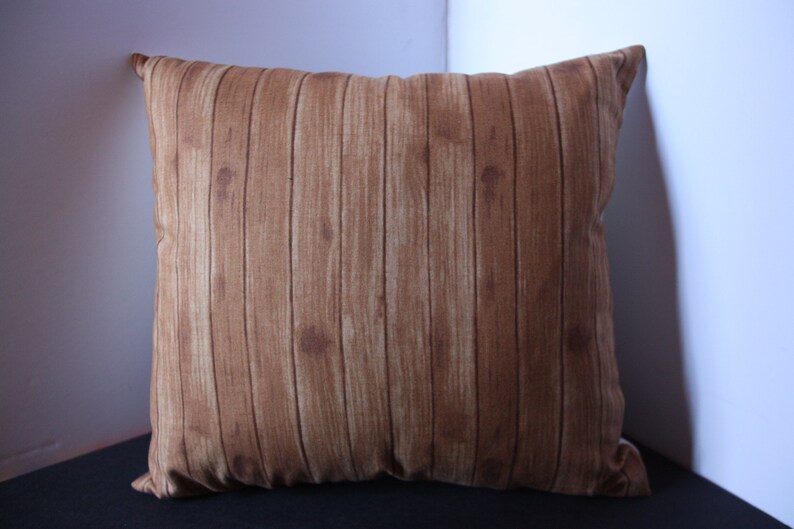May include: A brown throw pillow with a wood plank pattern.