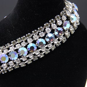May include: A silver bracelet with a row of iridescent blue rhinestones set in a silver chain.