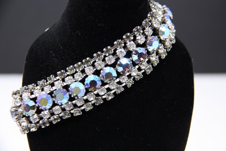 May include: A silver bracelet with a row of iridescent blue rhinestones set in a silver chain.