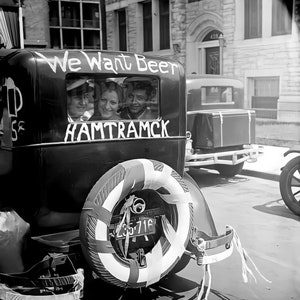 May include: A black and white photo of a vintage car with a sign that reads 