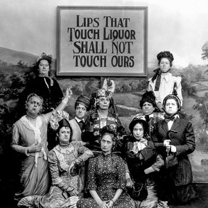 May include: A group of women in black and white clothing stand in front of a sign that reads 