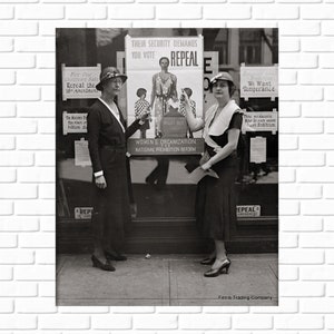 May include: Two women stand in front of a storefront window with signs advocating for the repeal of the 18th Amendment. The sign in the window reads 
