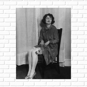 May include: A woman wearing a dark jacket and a white garter belt sits in a chair.