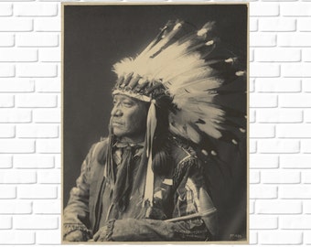 May include: A black and white photograph of a Native American man wearing a traditional headdress with feathers. He is looking off to the side and has a serious expression on his face.