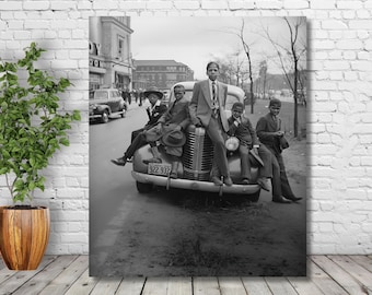 May include: Black and white photograph of five young men standing on the back of a vintage car. The car has a number plate that reads "922 937".