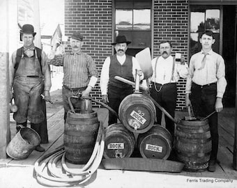 May include: Five men stand in front of a brick building, holding beer kegs and hoses. The kegs are labeled "Bock" and "3/2 Bock". The men are wearing hats and suspenders. The image is in black and white.