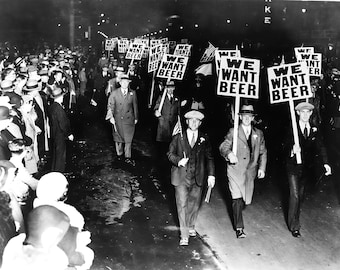 May include: A black and white photograph of a group of people protesting for the legalization of beer. The protesters are holding signs that read "We Want Beer".