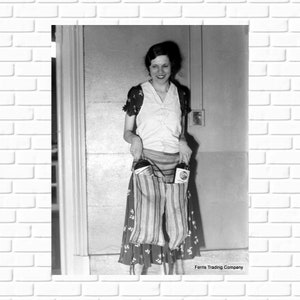 May include: A woman standing in a doorway holding two bags with striped fabric and a floral pattern. The bags contain bottles of a product labeled 