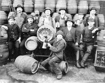 May include: Black and white photo of a group of men standing in front of a wall of wooden barrels. The men are wearing work clothes and hats. Some of the men are holding mugs. A sign on a barrel reads "Mark Bros. Wyndotte".