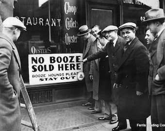 May include: A black and white photo of a group of men standing in front of a restaurant with a sign that reads "No Booze Sold Here. Booze Hounds Please Stay Out."