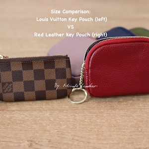 Puede incluir: Comparaci&oacute;n de tama&ntilde;o de dos llaveros. Un llavero a cuadros marr&oacute;n y beige con una cadena dorada y un llavero de cuero rojo con una cadena dorada. El texto "Comparaci&oacute;n de tama&ntilde;o: Llavero Louis Vuitton (izquierda) VS Llavero de cuero rojo (derecha)" est&aacute; por encima de los llaveros.