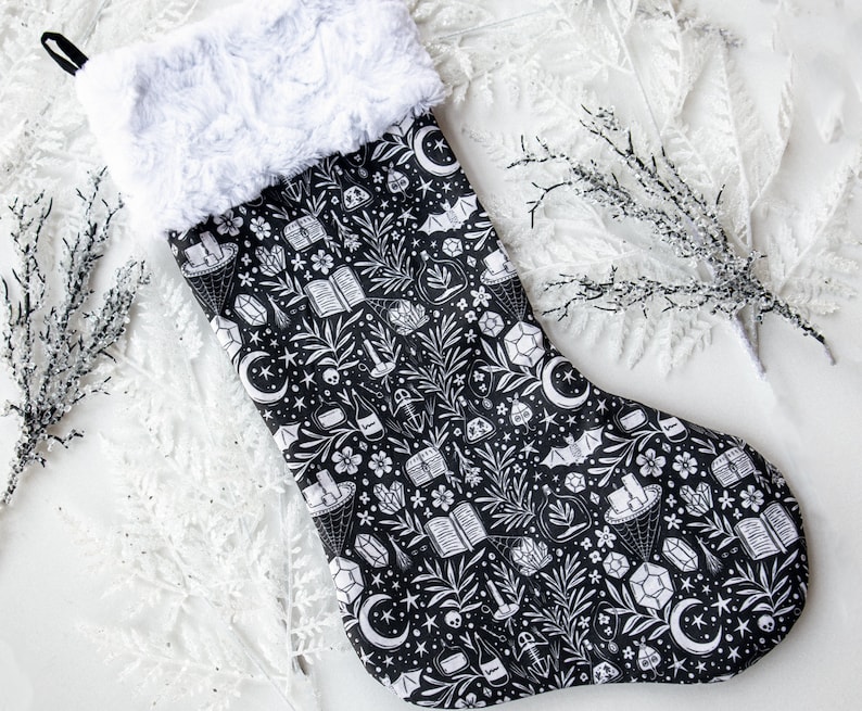 May include: Black and white Christmas stocking with a whimsical design featuring crystals, stars, bats, and other magical elements.