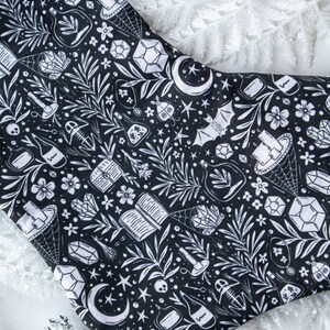 May include: Black and white stocking with a repeating pattern of crystals, moons, bats, and other witchy imagery.