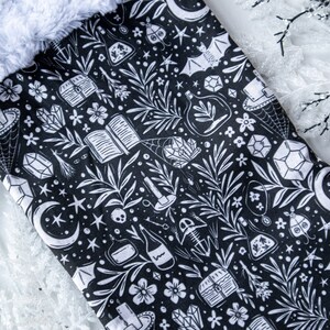 May include: Black and white Christmas stocking with a whimsical pattern of stars, moons, crystals, books, and other magical elements.