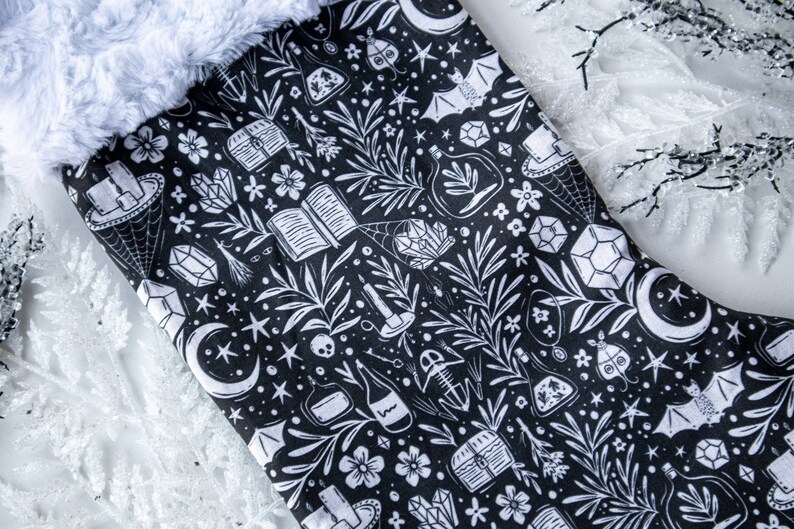 May include: Black and white Christmas stocking with a whimsical pattern of stars, moons, crystals, books, and other magical elements.