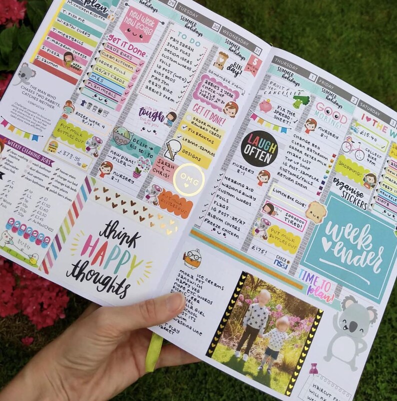 A hand holding a colorful and detailed planners or organizers with various sections for scheduling, reminders, and personal notes.