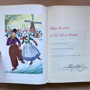 May include: An open book with a colorful illustration of two people ice skating in traditional Dutch attire. The illustration is set against a winter landscape with a windmill. The text on the right page reads "Hans Brinker or the Silver Skates".