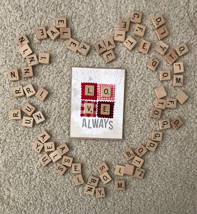 May include: A card with the word "ALWAYS" printed on it. The card is surrounded by letter tiles that spell out "LOVE" in red and white gingham fabric squares.