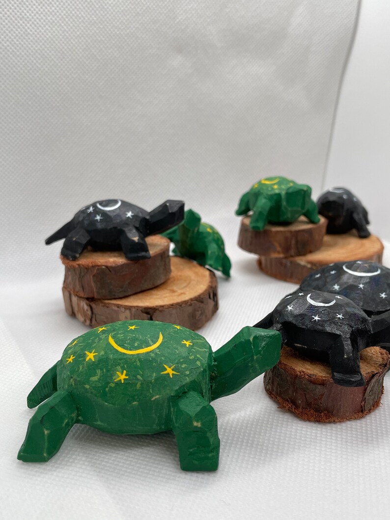 K&ouml;nnte beinhalten: F&uuml;nf h&ouml;lzerne Schildkr&ouml;tenfiguren, in Schwarz und Gr&uuml;n bemalt mit wei&szlig;en und gelben Sternen und Halbmonden. Die Schildkr&ouml;ten sitzen auf kleinen Holzscheiben.