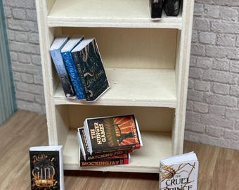 May include: A miniature wooden bookshelf with various miniature books, including "The Hunger Games", "Catching Fire", "Mockingjay", "The Cruel Prince", "Queen of Nothing", "To Kill a Kingdom", "Gild", and "Helfyre".