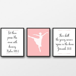 May include: Three framed prints with pink backgrounds and black frames. The center print features a white silhouette of a ballerina dancing. The left and right prints feature bible verses about dancing. The left print reads "Let them praise His name with dancing Psalm 149:3". The right print reads "Then shall the young women rejoice in the dance Jeremiah 31:13".