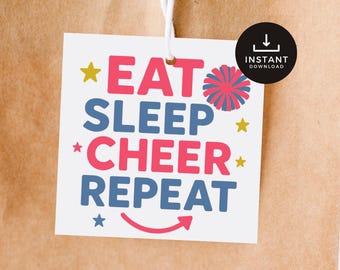 Może przedstawiać: Biała etykieta z napisem "EAT SLEEP CHEER REPEAT" w kolorze różowym i niebieskim, z grafiką gwiazd i pomponów. Etykieta jest przymocowana do brązowej papierowej torby z białym sznurkiem. Czarny okrąg z napisem "INSTANT DOWNLOAD" znajduje się w prawym górnym rogu.