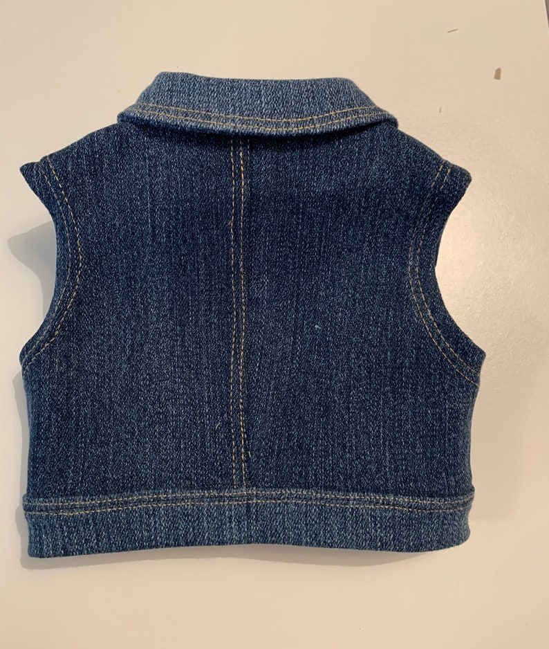 May include: A blue denim vest with a collared neckline and sleeveless design.