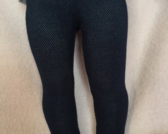 May include: Dark blue denim leggings for a doll. The leggings have a textured look and are made of a soft, stretchy fabric.