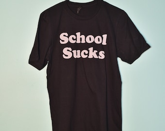 May include: Black t-shirt with the text "School Sucks" printed in pink letters.