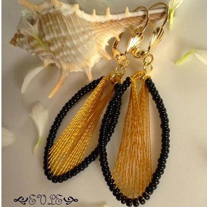 May include: A pair of gold and black earrings with a fringe design. The earrings are made with black beads and gold thread.