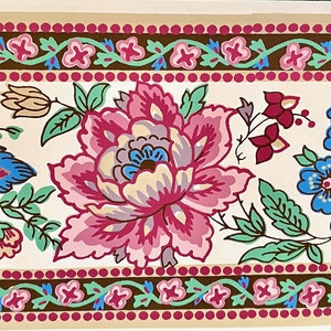 May include: A decorative floral border featuring a repeating pattern of large, stylized flowers in shades of pink, blue, and green. The flowers are set against a cream background, with a brown and pink dotted border.