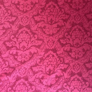 May include: A vibrant fuchsia fabric featuring a repeating damask pattern in a darker shade of magenta. The intricate design consists of symmetrical floral and leaf motifs that create a dense, continuous texture across the entire surface of the textile.