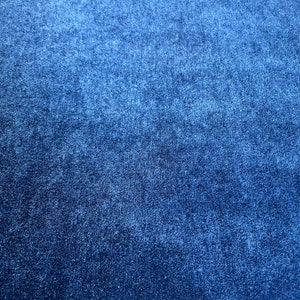 May include: A close-up of a dark blue textured fabric. The fabric has a slightly grainy appearance.