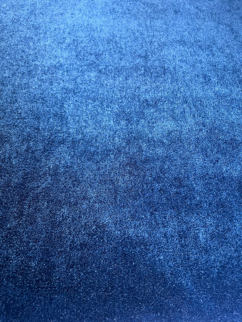May include: A close-up of a dark blue textured fabric. The fabric has a slightly grainy appearance.