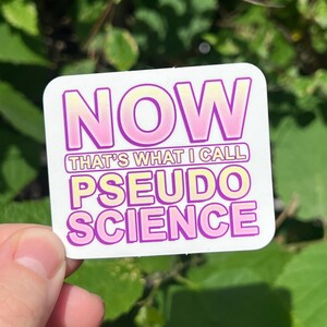 May include: A white sticker with the text "NOW THAT'S WHAT I CALL PSEUDO SCIENCE" in pink and yellow letters. The text "NOW" is in a large font and the rest of the text is in a smaller font.