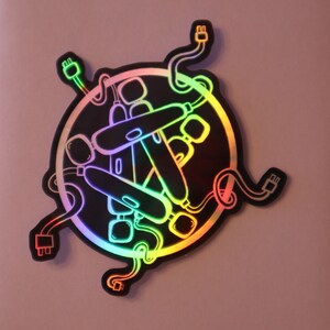 May include: A black and white sticker with a rainbow iridescent finish. The sticker features a circular design with multiple cords and plugs intertwined. The cords and plugs are stylized and resemble a tangled mess.