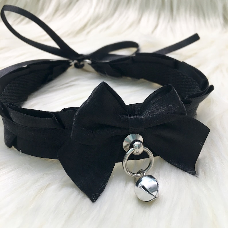 May include: Black satin choker with a large black bow and a silver bell charm.