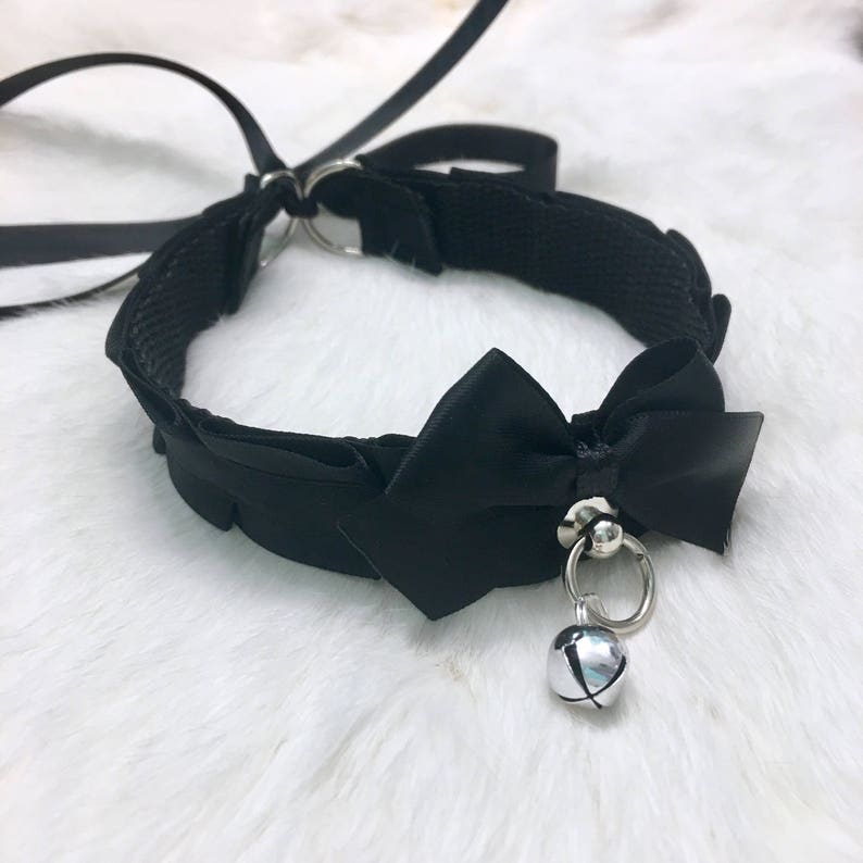 May include: Black choker necklace with a large black satin bow and a silver bell charm.