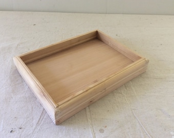 Puede incluir: Una bandeja de madera simple con forma rectangular y una superficie lisa y sin terminar.