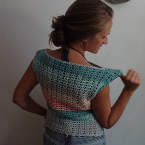 Puede incluir: Un top de crochet sin mangas con un patr&oacute;n a rayas en tonos de azul, rosa y beige. El top tiene un escote amplio y redondo y un ajuste holgado.