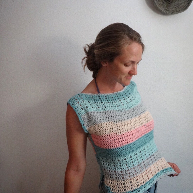 Puede incluir: Un top de crochet con un patr&oacute;n de rayas en tonos de azul, rosa y beige. El top tiene un cuello de barco y es sin mangas.