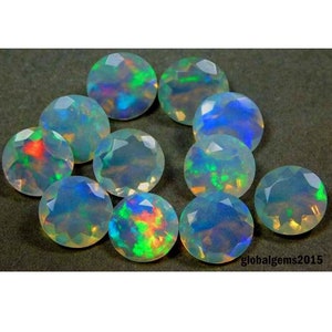 May include: Ten round, iridescent opal gemstones with a white base and flashes of green, blue, and red.