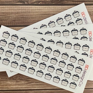 May include: Sheets of stickers featuring a cartoon-style slow cooker design. The stickers are square with a light gray pot, a dark gray lid, and a smiling face. The text "BDdesignCo" is printed on the side of each sheet.