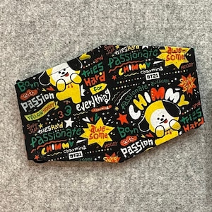 May include: Two black fabric face masks with a green fabric backing. The masks feature a cartoon character with the text "Born with Passion", "Tries Hard for Everything", "Passionate", "Awesome", "Super Star", "Charming", "BT21", "ChimmY", and "Yellow Hoody".