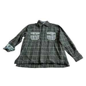 May include: A long-sleeve button-down shirt in a dark gray fabric with a white grid pattern. The shirt features two chest pockets with a white and gray checkered print, a pointed collar, and a light blue patterned lining visible on the cuffs.