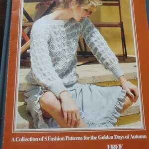 May include: A magazine cover featuring a woman wearing a light blue knitted sweater and skirt. The cover text reads "Autumn Harvest" and "A Collection of 5 Fashion Patterns for the Golden Days of Autumn". The magazine is advertising a free pattern from Thorobred Scheepjeswol.