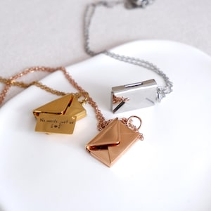 May include: Three gold, rose gold, and silver necklaces with envelope-shaped pendants. The gold pendant has the inscription "No words, just us S♡J".