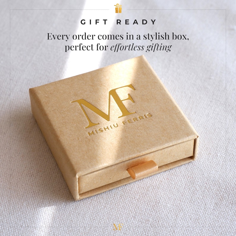 May include: A tan gift box with a drawer, featuring gold lettering of the initials "MF" and the brand name "Mishiu Ferris." The text "GIFT READY" is at the top. The box is designed for effortless gifting.